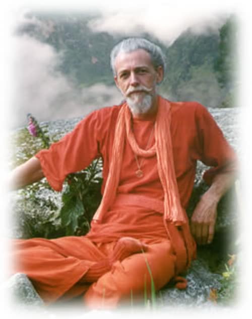 Muz Murray seated in the hills of Portugal wearing saffron orange robe
